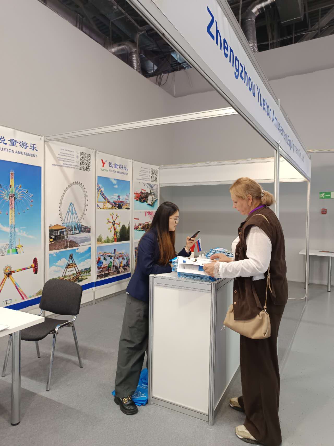 Zhengzhou Yueton Amusement Equipment booth at RAAPA Autumn 2026 in Moscow, showing ferris wheel and flying chair panels